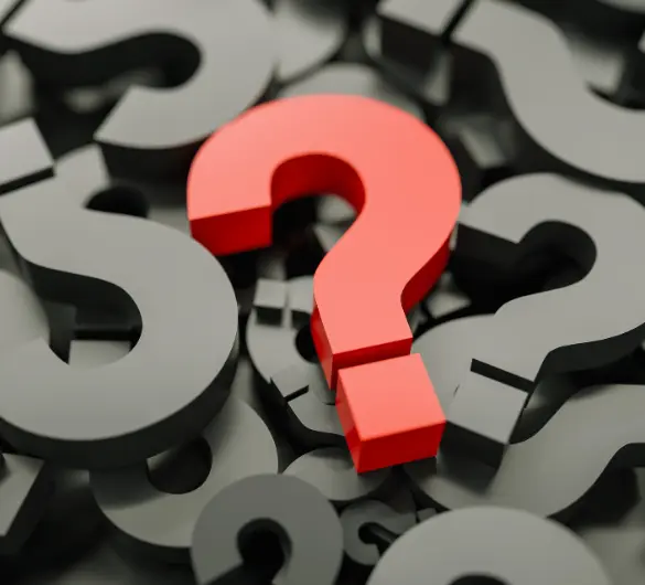 
A single prominent red question mark stands out in the center of the frame, surrounded by a pile of numerous dark gray question marks, creating a sense of inquiry and confusion.