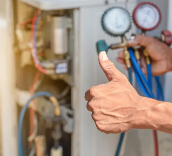 A close-up shows a person's hand giving a thumbs-up gesture in the foreground, with an air conditioning unit and pressure gauges held by another hand in the background, suggesting successful repair or maintenance.